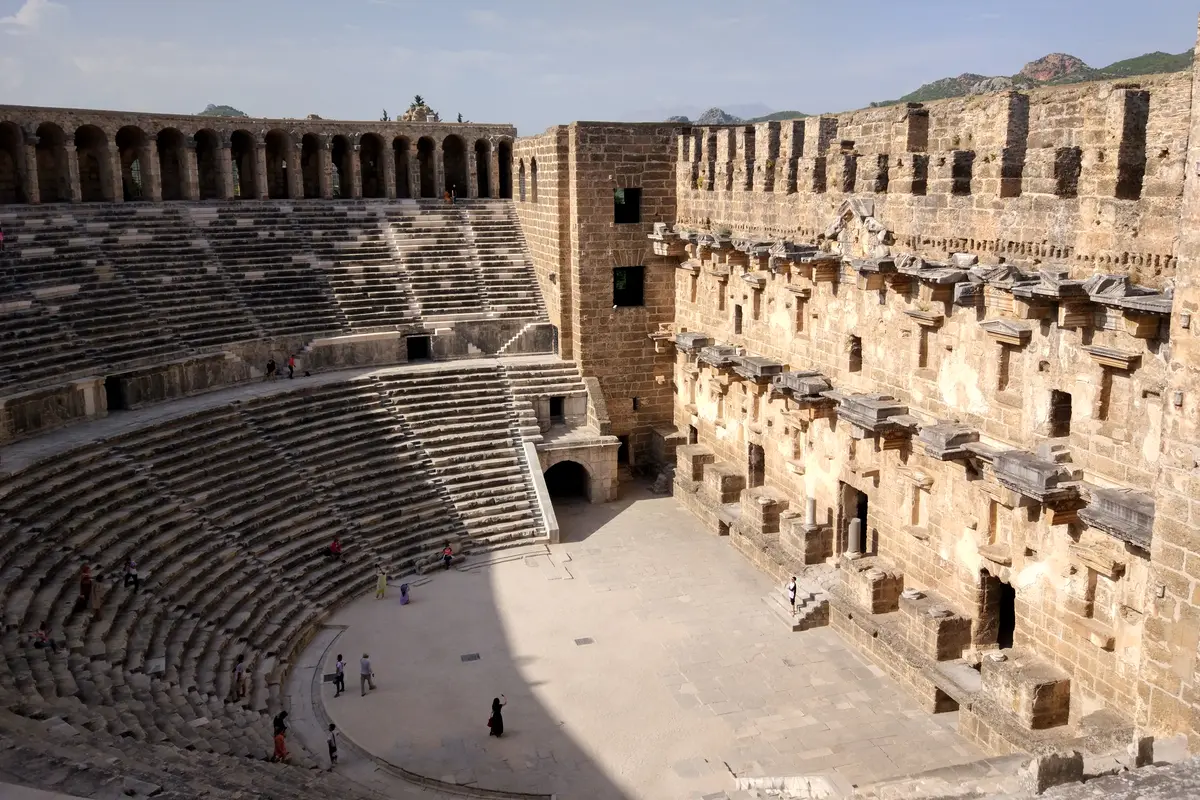 The Roman theatre of Aspendos seen from its top row, with curved stone seating on the left and the tall stage building on the right